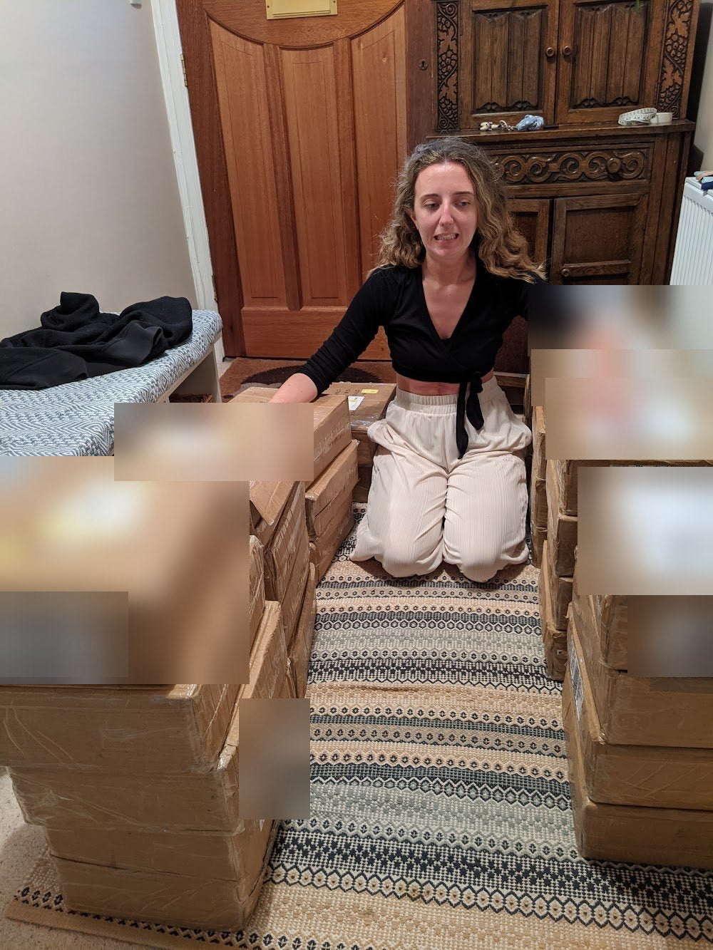 Lucy kneeling among stacked delivery boxes